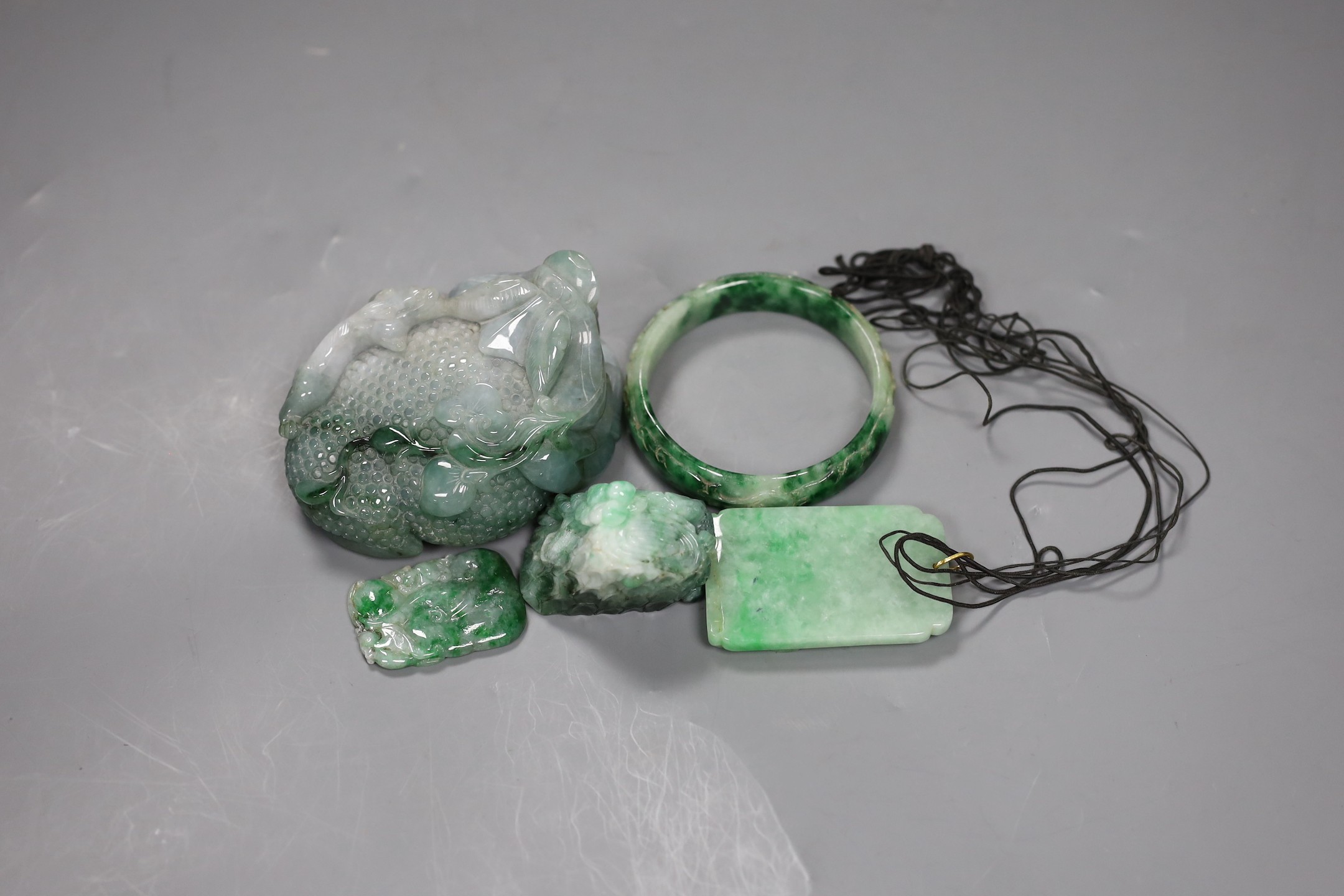 A group of five Chinese jadeite carvings, including two pendants and a bangle, largest 11cms long
